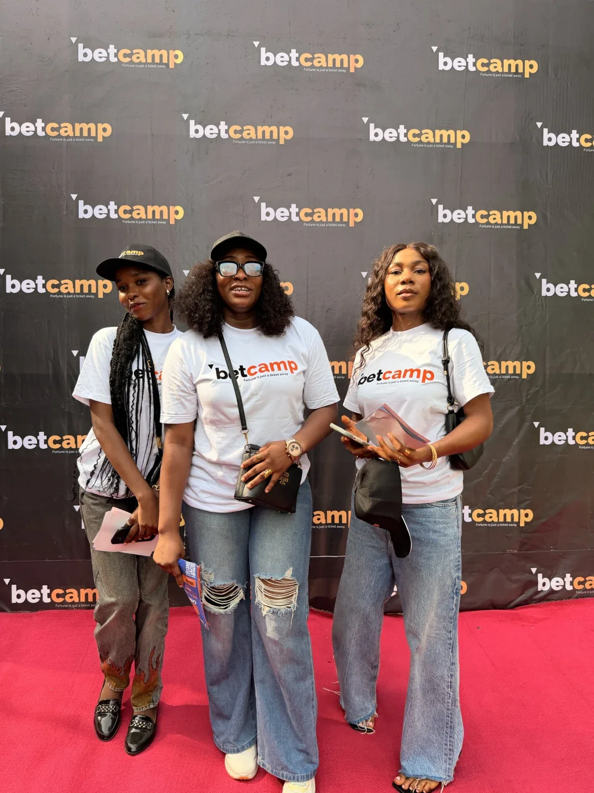 Three attendees at a Betcamp event in front of the branded backdrop